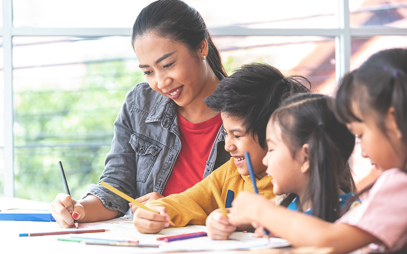 Teacher guiding students through continuous assessment in a primary classroom.