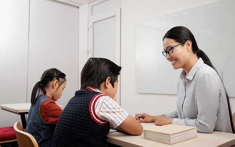 two students receiving close guidance from a teacher