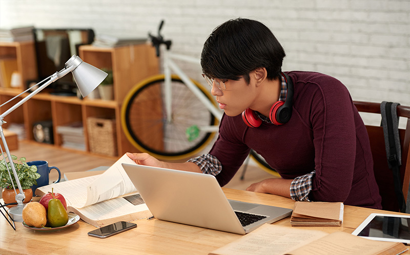 Student focusing on studies with laptop and books