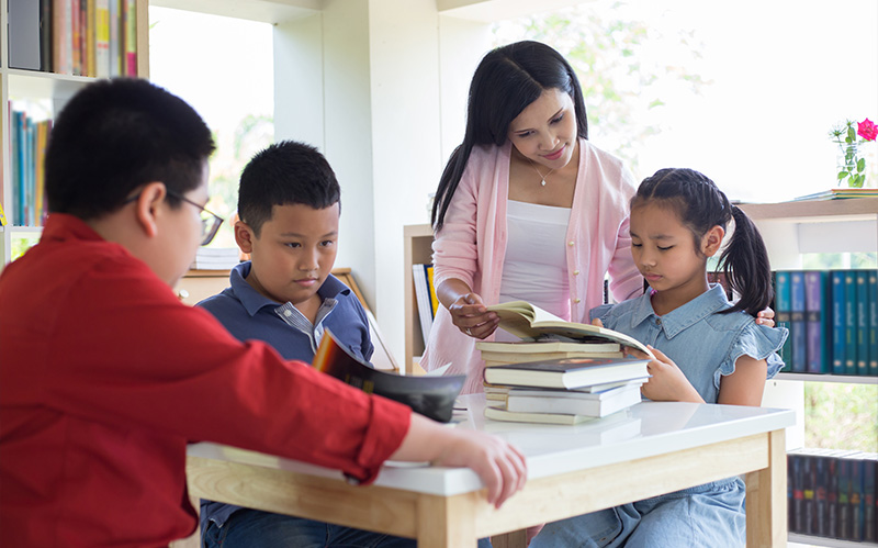 students studying together in a classroom environment guided by a teacher